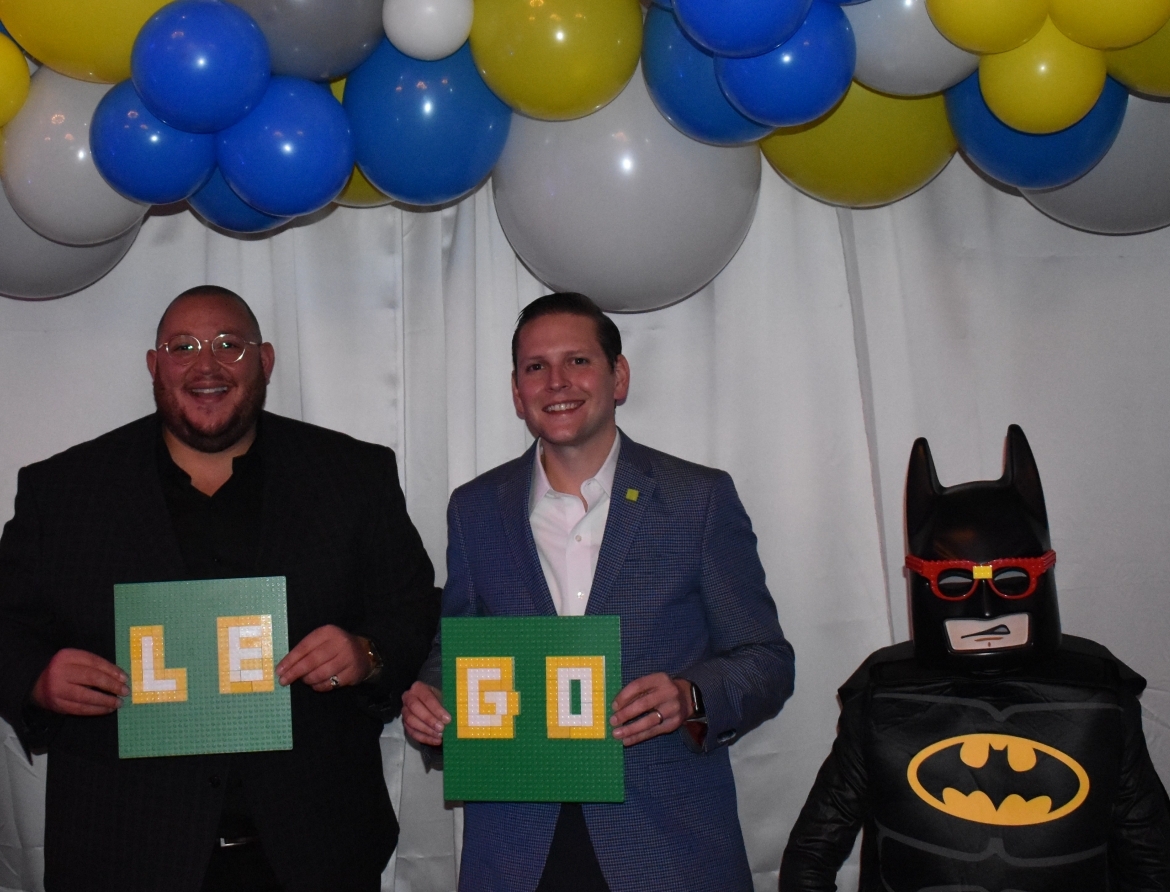 Two people holding signs that say "LEGO" with Batman